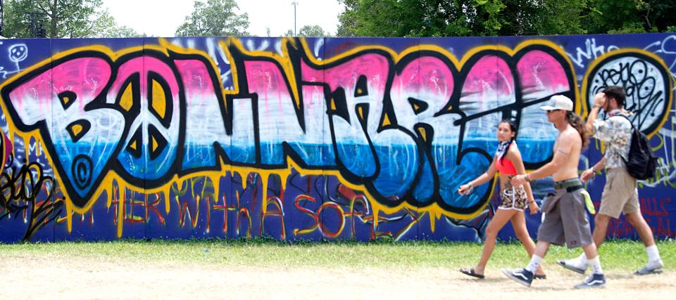 Music fans walk past artwork and graffiti at the campground at Bonnaroo Music and Arts Festival on Sunday, June 16, 2019 in Manchester, Tenn. 