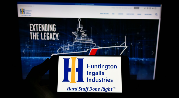 Person holding smartphone with logo of US company Huntington Ingalls Industries Inc (HII) on screen in front of website Focus on phone display