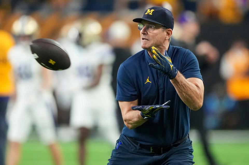 Michigan head coach Jim Harbaugh looks to catch a pass during warm ups ahead of the College Football Playoff national championship game against Washington at NRG Stadium in Houston, Texas on Monday, January 8, 2024.