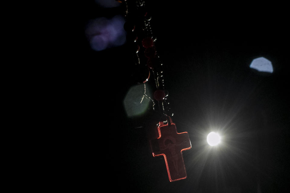 A parishioner's cross is illuminated during an outdoor Mass marking the feast day of Saint George, in Rio de Janeiro, Brazil, April 23, 2024. (AP Photo/Bruna Prado)