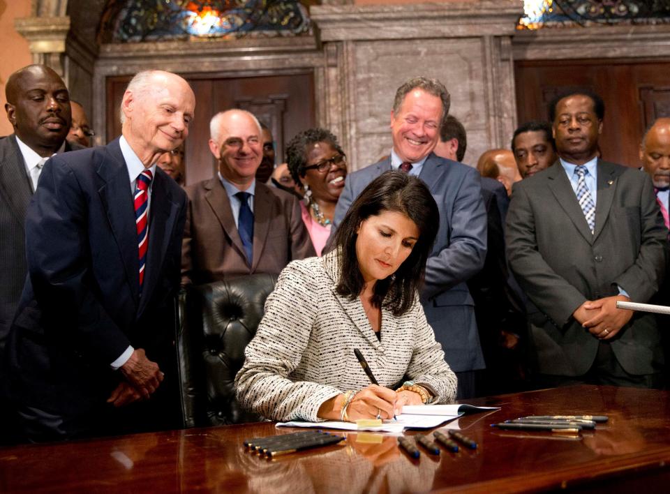 South Carolina Gov. Nikki Haley signs a bill into law as former South Carolina governors and officials look on, at the Statehouse in Columbia, S.C., on July 9, 2015.