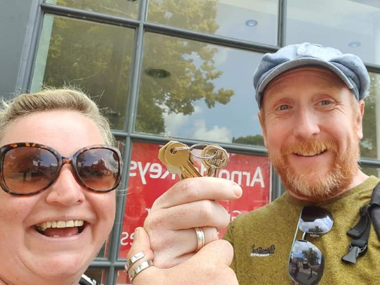 Woman and man holding a key and looking at the camera