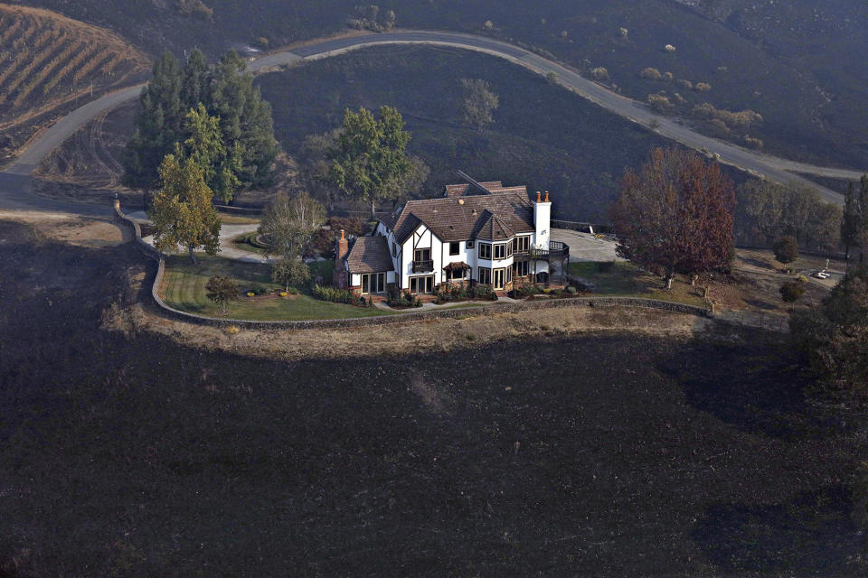 A home between Healdsburg and Windsor, Calif., on Tuesday, Oct. 29, 2019, is surrounded by charred ground but was spared from the Kincade Fire flames. Frustration and anger mounted across Northern California on Tuesday as the state’s biggest utility, Pacific Gas & Electric, began another round of widespread blackouts aimed at preventing its electrical equipment from sparking wildfires in high winds. (Guy Wathen/San Francisco Chronicle via AP)