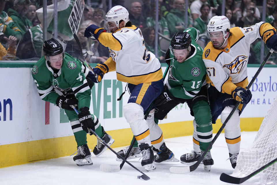 Dallas Stars' Fredrik Olofsson (42) and Radek Faksa (12) work against Nashville Predators' Mark Jankowski, second from left, and Dante Fabbro (57) for control of the puck in the first period of an NHL hockey game, Monday, April 3, 2023, in Dallas. (AP Photo/Tony Gutierrez)