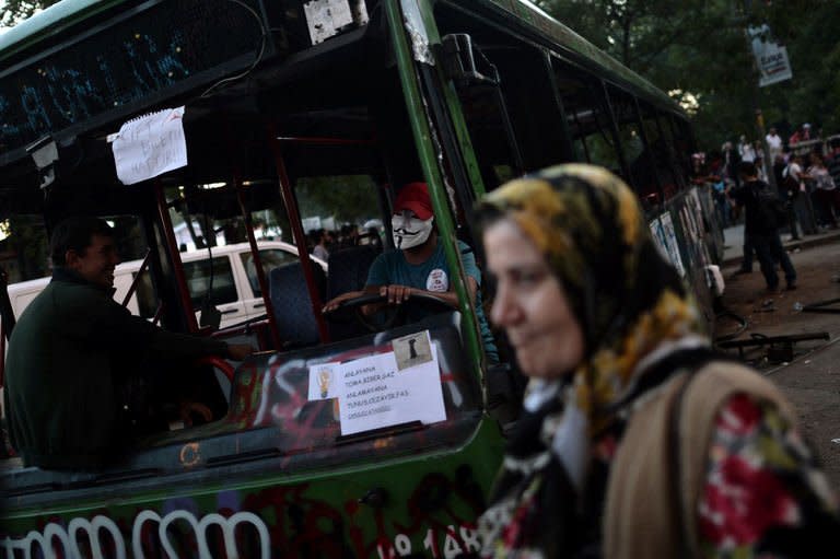 Demonstrators sit inside a destroyed bus at Taksim Square in Istanbul on June 6, 2013