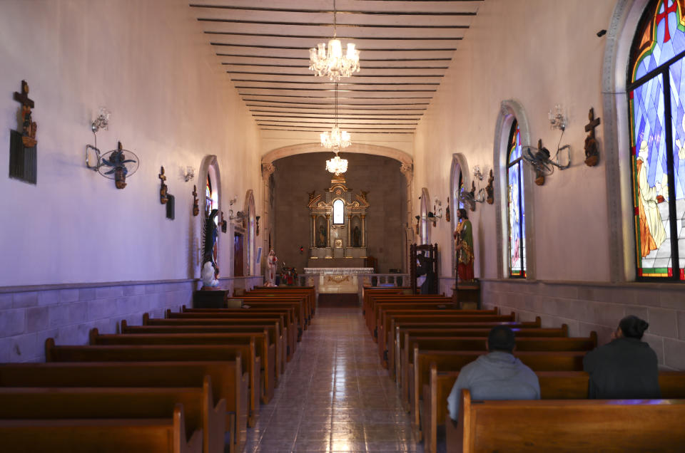 People pray inside the church in Villa Union, Mexico, Tuesday, Dec. 3, 2019. Villa Union bears the scars of the hourslong gun battles Saturday and Sunday. The fight that unfolded between a cartel force estimated at 100 to 150 men and state police left 23 people dead. Many homes and buildings were riddled with bullet holes. (AP Photo/Eduardo Verdugo)