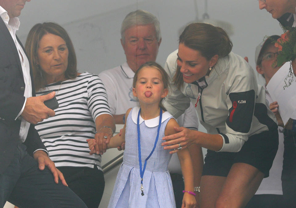 Princess Charlotte, flanked by her grandmother and mother, gestures through a window at the prize giving after the King's Cup regatta. (Photo: PA Wire/PA Images)