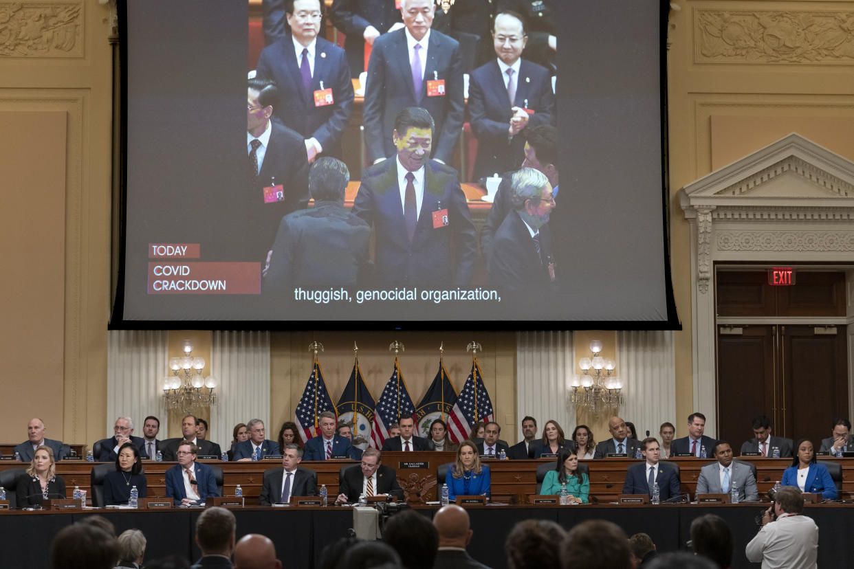 A video showing Chinese leader Xi Jinping is displayed on a screen above a panel of officials.