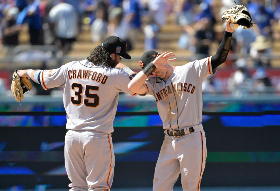 San Francisco Giants shortstop Brandon Crawford (35) and center fielder Mike Yastrzemski gesture after defeating the Los Angeles Dodgers at Dodger Stadium on Sunday.