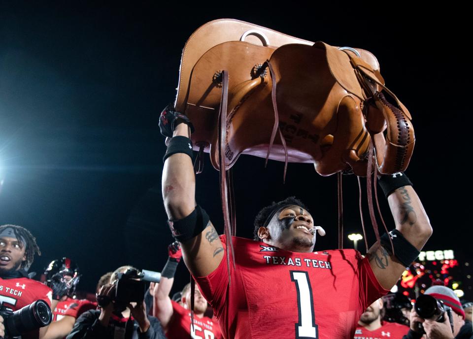 Texas Tech's defensive back Dadrion Taylor-Demerson (1) holds up the Saddle Trophy after the team's win against TCU, Thursday, Nov. 2, 2023, at Jones AT&T Stadium.