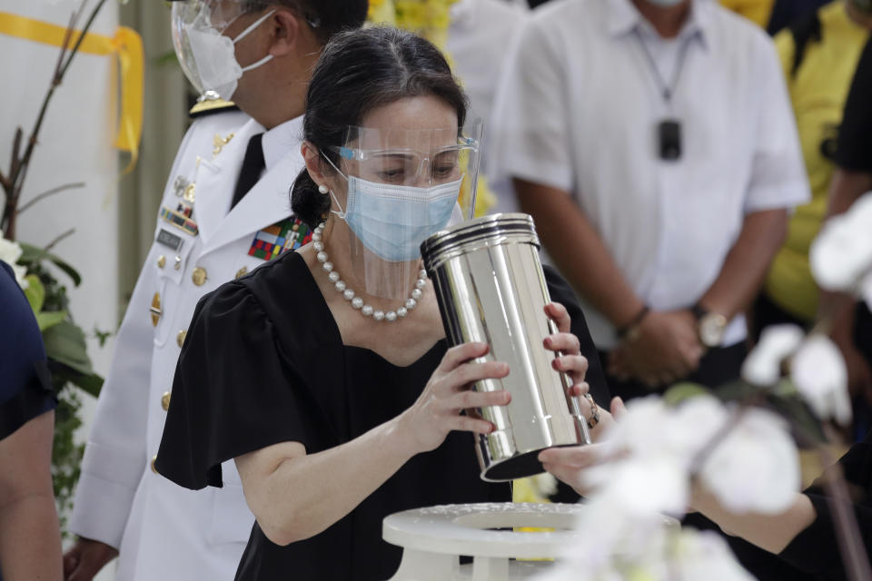 Ballsy Aquino-Cruz holds the urn of her brother former Philippine President Benigno Aquino III before he is placed on the tomb on Saturday, June 26, 2021 at a memorial park in suburban Paranaque city, Philippines. Aquino was buried in austere state rites during the pandemic Saturday with many remembering him for standing up to China over territorial disputes, striking a peace deal with Muslim guerrillas and defending democracy in a Southeast Asian nation where his parents helped topple a dictator. He was 61. (AP Photo/Aaron Favila)