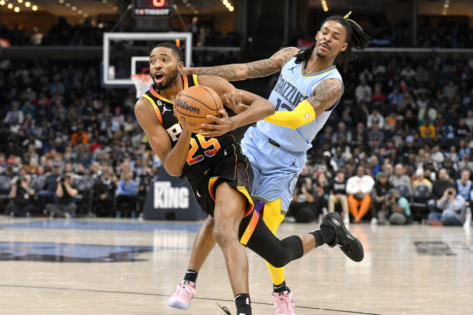Phoenix Suns forward Mikal Bridges (25) drives against Memphis Grizzlies guard Ja Morant in the first half of an NBA basketball game, Monday, Jan. 16, 2023, in Memphis, Tenn. (AP Photo/Brandon Dill)