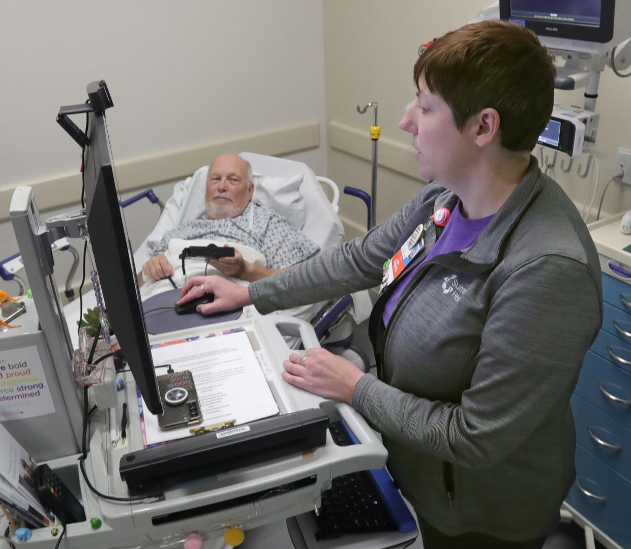 Summa Akron City Hospital patient access liaison Veronica Peteya checks in Gene Hertzig before his surgery July 13 in Akron.