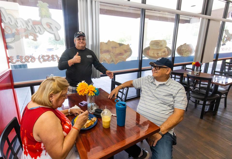 Paradise Bakery & Cuban Food co-owner Roberto Caparros, center, talks with customers Elba Reyes, left, and Jorge Castaneda, right, as they enjoyed their lunch on July 12.