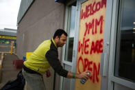 Convenience store manager Sunny Katoch paints a welcome sign on the back door as residents begin to flood back into their city after being evacuated due to raging wildfires in Fort McMurray, Alberta, Canada, June 1, 2016. REUTERS/Topher Seguin