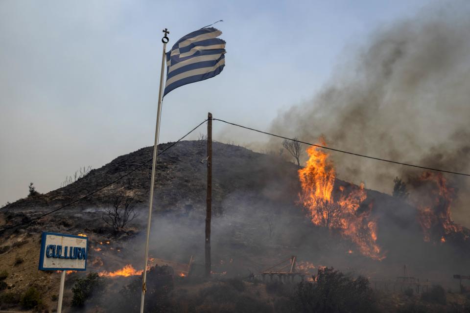 Flames burn a hill on the Aegean Sea island of Rhodes, southeastern Greece, on Monday, July 24, 2023. A weeklong wildfire on the Greek island of Rhodes has torn past defenses, forcing more evacuations, as three major fires rage elsewhere in the country fueled by strong winds and successive heat waves. (AP Photo/Petros Giannakouris)