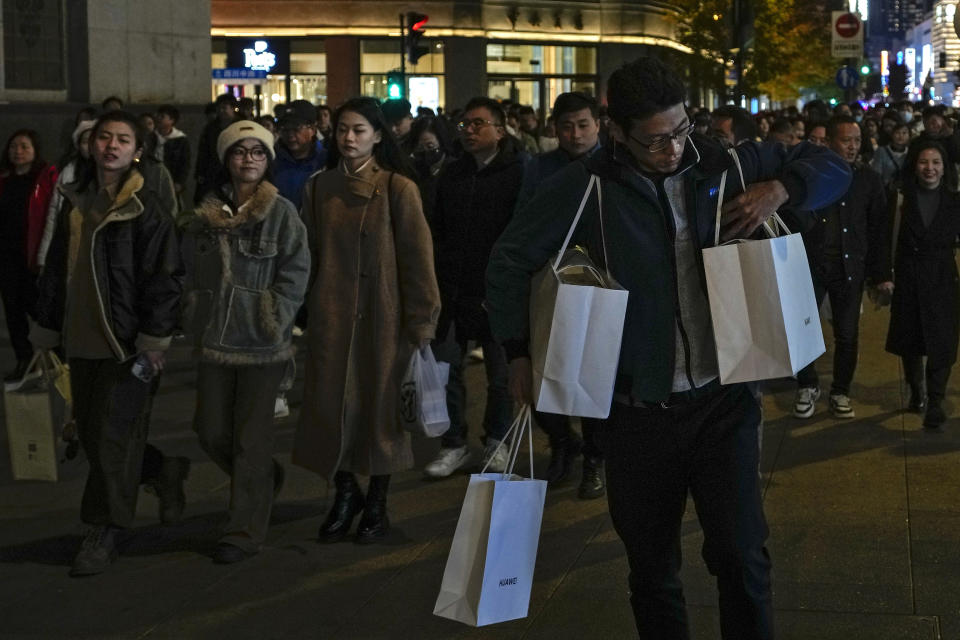 A man adjusts his bag of purchased goods as visitors tour at a Nanjing pedestrian shopping street in Shanghai, China on Nov. 25, 2023. Chinese leaders have wrapped up a two-day annual meeting to set economic priorities for the coming year, the official Xinhua News Agency reported Tuesday, Dec. 12, 2023 without giving details of what was decided. (AP Photo/Andy Wong)
