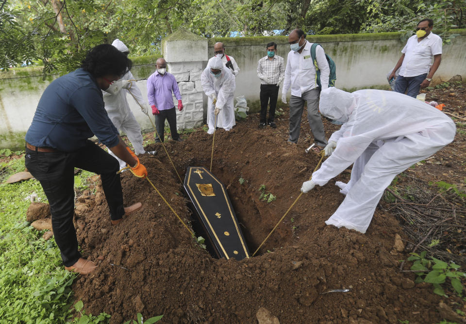 People lower the coffin of a man who died of COVID-19, at a cemetery in Mumbai, India, Tuesday, June 23, 2020. Some Indian states Tuesday were considering fresh lockdown measures to try to halt the spread of the virus in the nation of more than 1.3 billion. (AP Photo/Rafiq Maqbool)