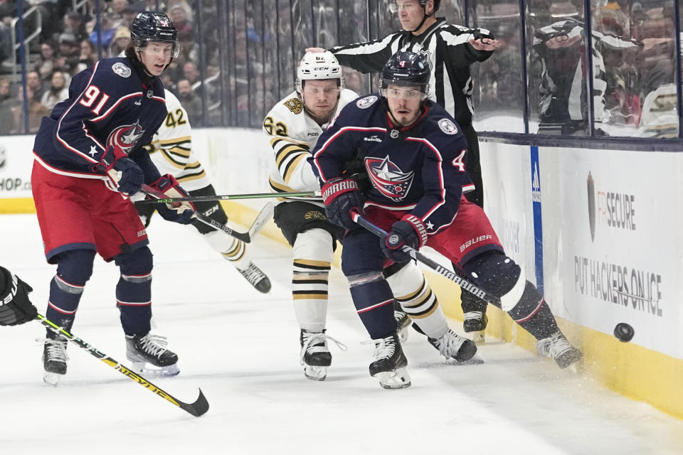 Columbus Blue Jackets center Cole Sillinger (4) dumps the puck in front of teammate Kent Johnson (91) ad Boston Bruins center Oskar Steen (62) in the second period of an NHL hockey game Tuesday, Jan. 2, 2024, in Columbus, Ohio. (AP Photo/Sue Ogrocki)