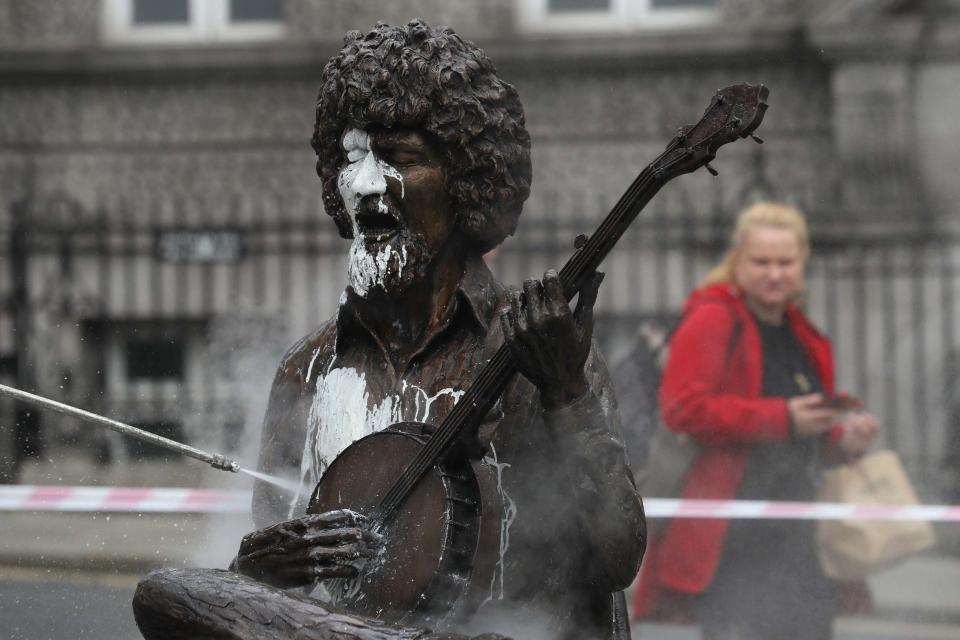 The vandalised statue is hosed down (PA)