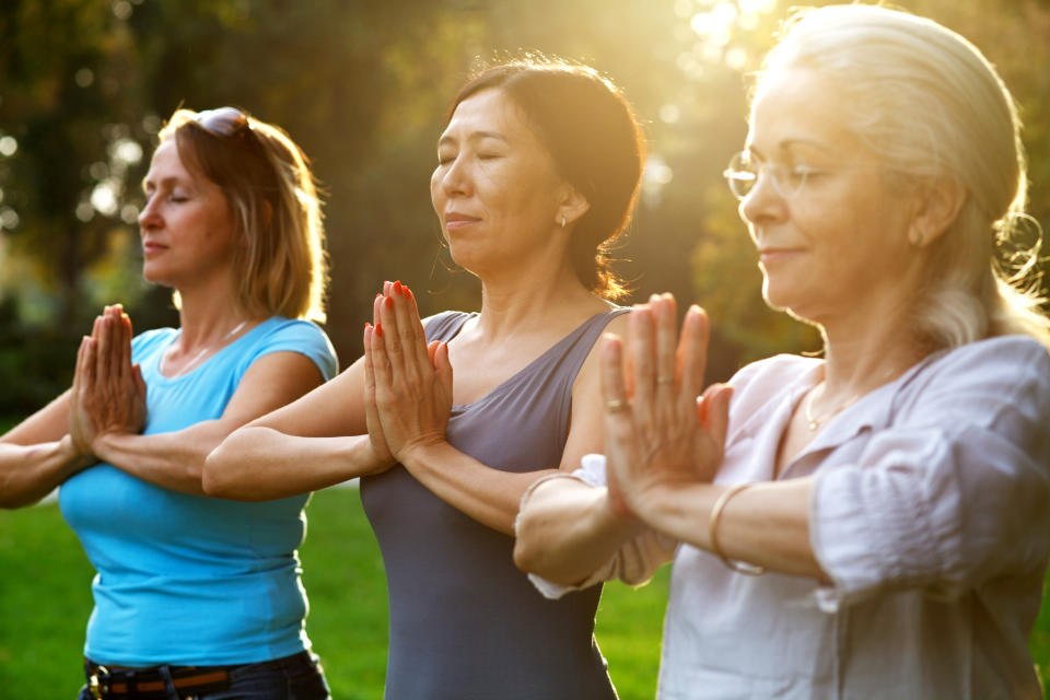 Three mature ladies doing yoga outdoors