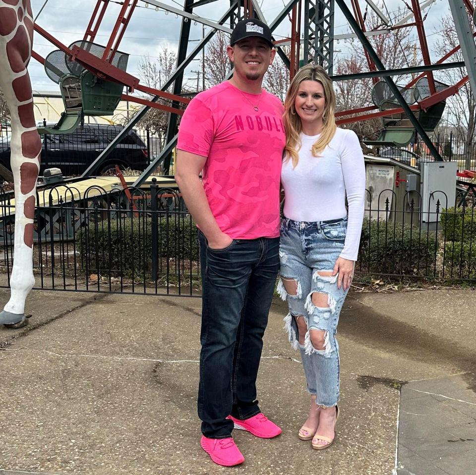 Chris and Paige McCoy stand in front of a giraffe statue and the Ferris wheel at The Park at West End/ Garrison set to reopen in the Fort Smith downtown entertainment district by May 2023.