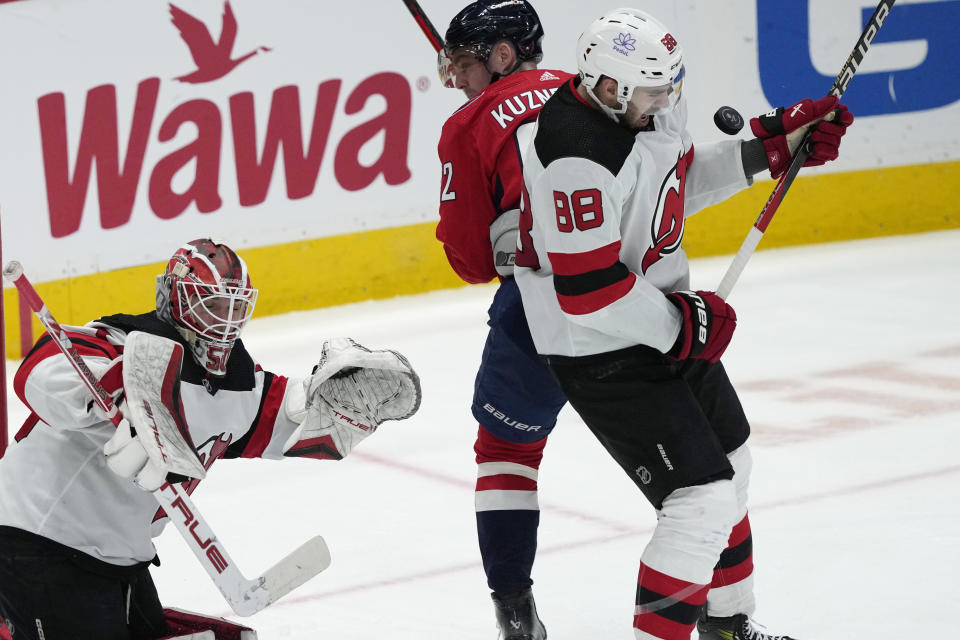 The puck bounces off New Jersey Devils defenseman Kevin Bahl (88), who is next to Washington Capitals center Evgeny Kuznetsov (92), while Devils goaltender Nico Daws (50) looks for the puck during the third per hockey game Wednesday, Jan. 3, 2024. (AP Photo/Susan Walsh)