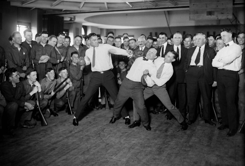 harry houdini cannot escape the hold of boxer benny leonard and jack dempsey prepare to swing