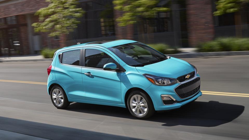 Blue Chevrolet Spark driving on city street.