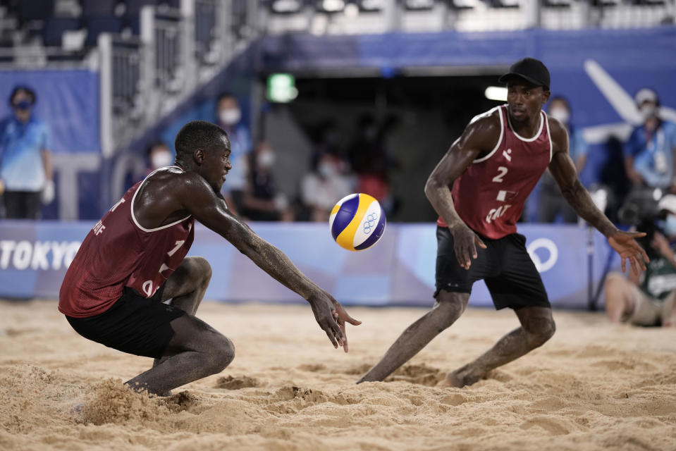 Cherif Younosse, left, of Qatar, returns a shot as teammate Ahmed Tijan watches during a men's beach volleyball semifinal match against the Russian Olympic Committee at the 2020 Summer Olympics, Thursday, Aug. 5, 2021, in Tokyo, Japan. (AP Photo/Felipe Dana)