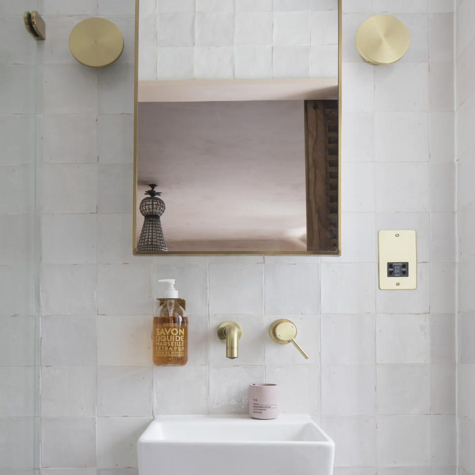 White bathroom with gold hardware and mirror