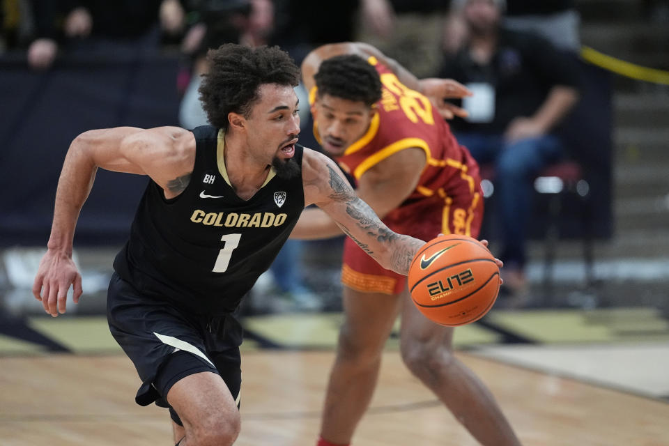 Colorado guard J'Vonne Hadley, front, scoops up the ball next to Southern California forward Arrinten Page during the second half of an NCAA college basketball game Saturday, Jan. 13, 2024, in Boulder, Colo. (AP Photo/David Zalubowski)