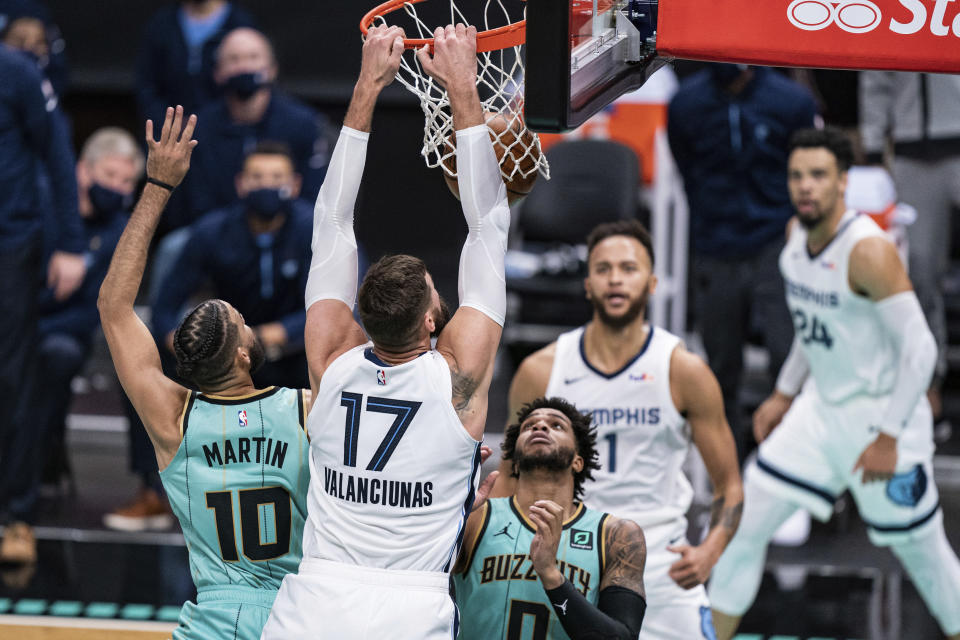 Memphis Grizzlies center Jonas Valanciunas (17) dunks over Charlotte Hornets forward Caleb Martin (10) and forward Miles Bridges (0) during the second half of an NBA basketball game in Charlotte, N.C., Friday, Jan. 1, 2021. (AP Photo/Jacob Kupferman)