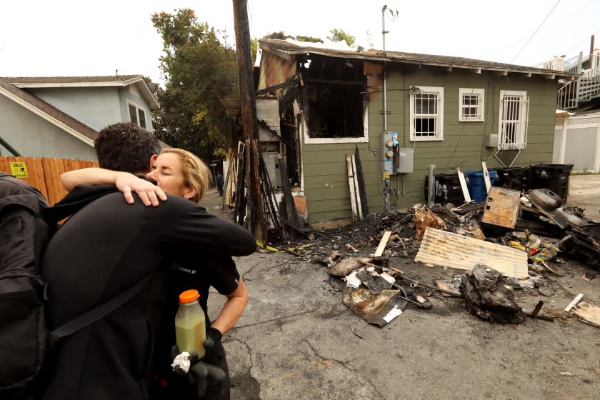 VENICE, CA - APRIL 21, 2021 - - Pediatrician Courtney Gillenwater, facing, receives a hug of support from Brian Averill, with Venice Boardwalk Action Committee, in front of her fire damaged home at 31 E. Clubhouse Avenue in Venice on April 21, 2021. The fire is under investigation but residents in the neighborhood believe it may have been set by new homeless in the area. Gillenwater's dog Togo died in the fire. Gillenwater is familiar with the homeless in the area and has been able to get along even bringing them water and food from time to time. But there were new homeless in the area that were not as receptive. The fire started around 3 a.m. Wednesday according to the Los Angeles Fire Department. Arson investigators were on the scene trying to determine the cause of the fire. Residents and neighbors have been having problems with some of the homeless in the area. (Genaro Molina / Los Angeles Times)