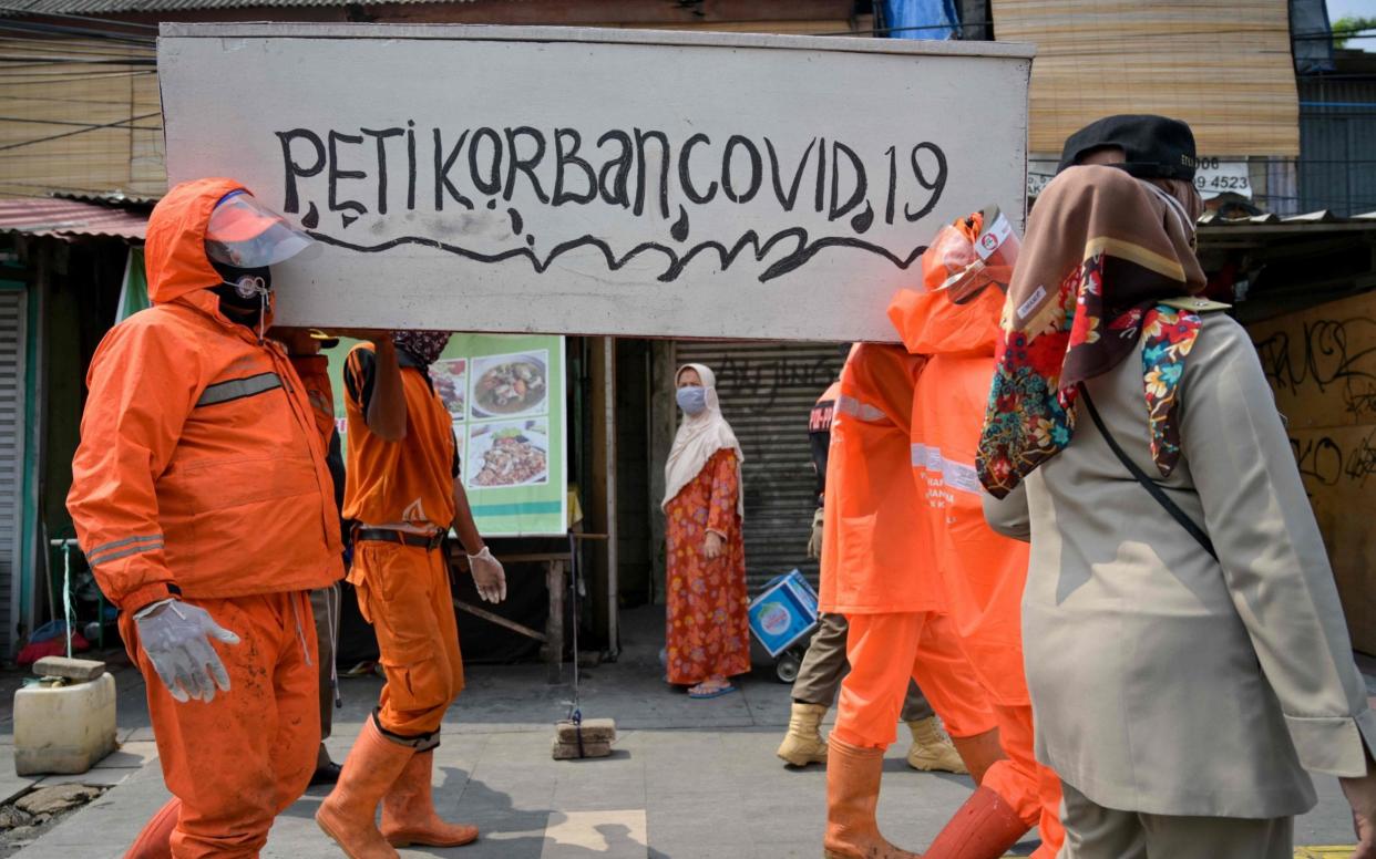 Workers carry a fake coffin - used to shock people into taking precautions against Covid-19 - Bay Ismoyo/AFP