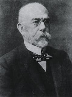 Black and white photograph of scientist Robert Koch, wearing spectacles and a large moustache.