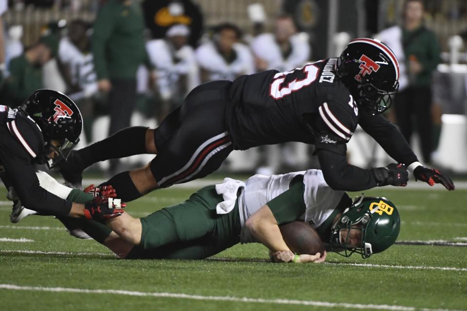 Baylor quarterback Blake Shapen, bottom right, is tackled by Texas Tech linebacker Jacob Rodriguez (13) and defensive back Dadrion Taylor-Demerson, left, during the second half of an NCAA college football game Saturday, Oct. 29, 2022, in Lubbock, Texas. (AP Photo/Justin Rex)