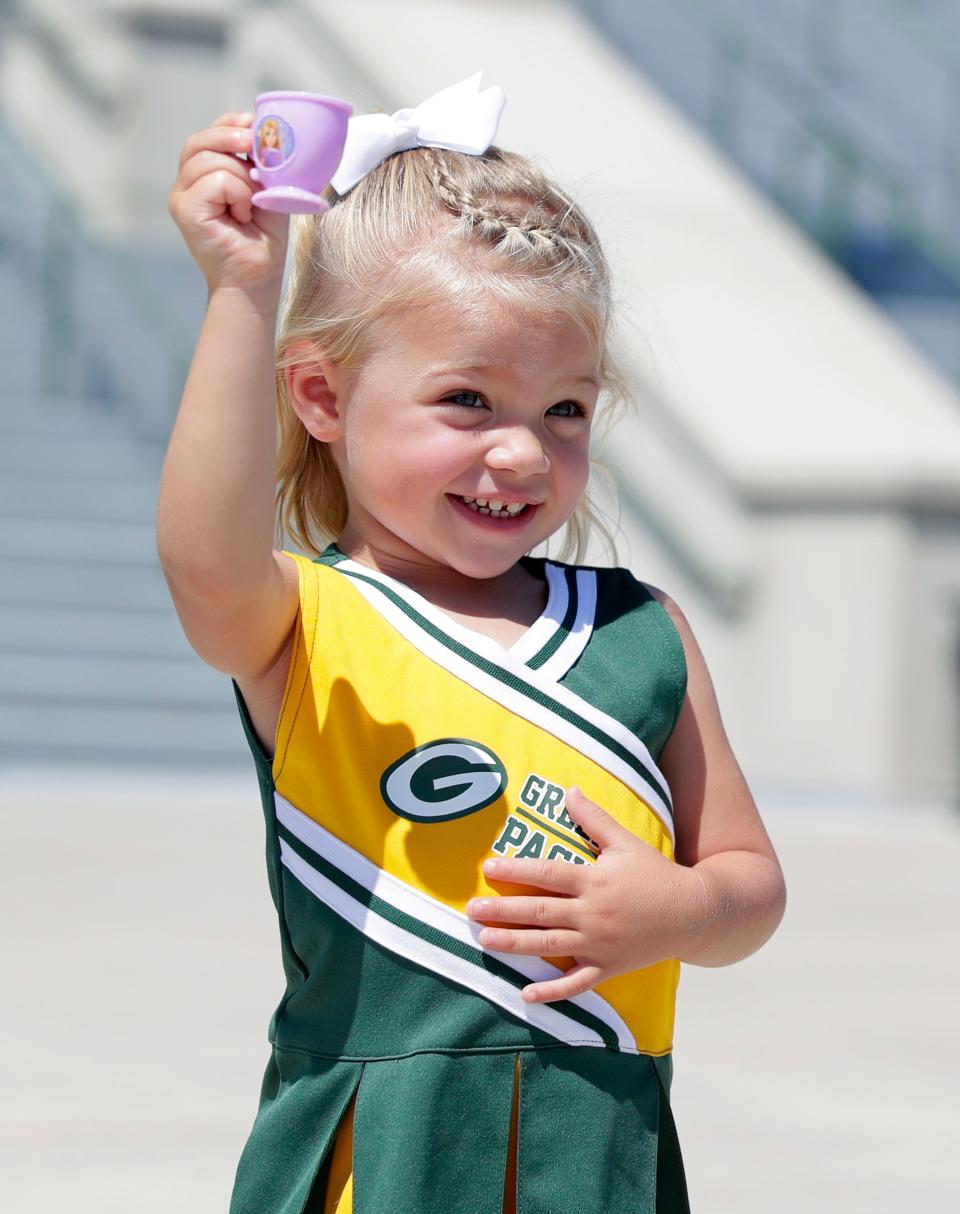 Two-year-old Aria Rubens of De Pere shows off one of the Disney princess teacups she offers to Green Bay Packers players after training camp on Wednesday.