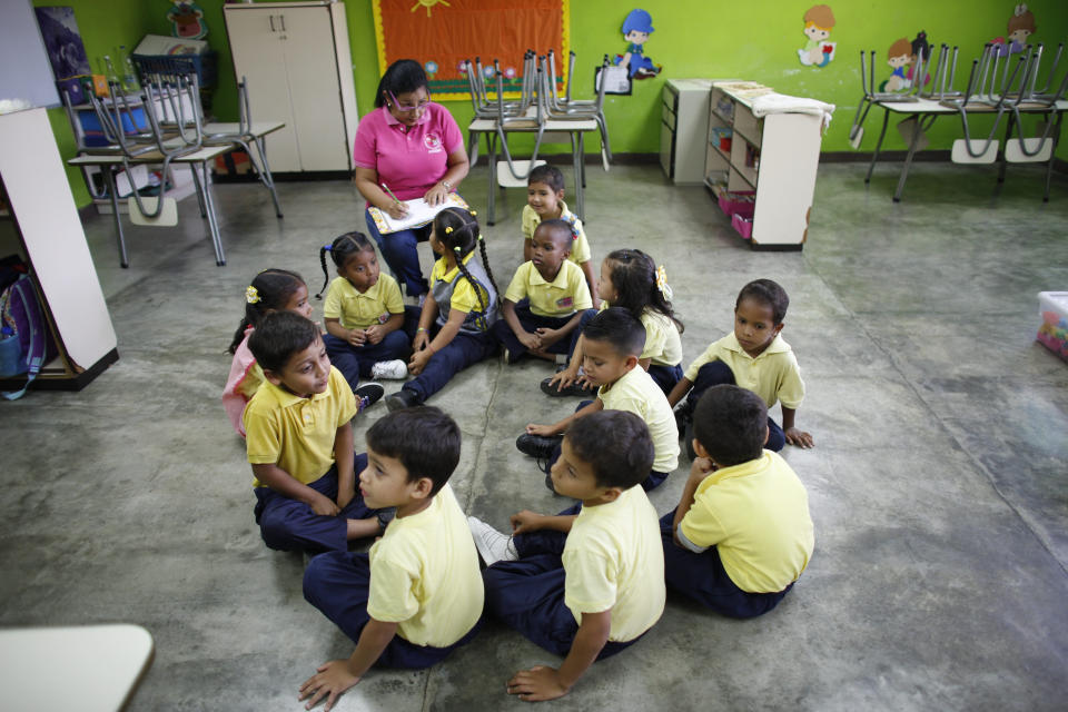 In this Oct. 7, 2019 photo, teacher Daixy Aguero take notes as she teaches her class at a school in Caracas, Venezuela. Nearly half of the Venezuela’s teachers have fled the country in the last three years, according to workers union representing educators. They’re escaping low pay and crumbling classrooms. (AP Photo/Ariana Cubillos)