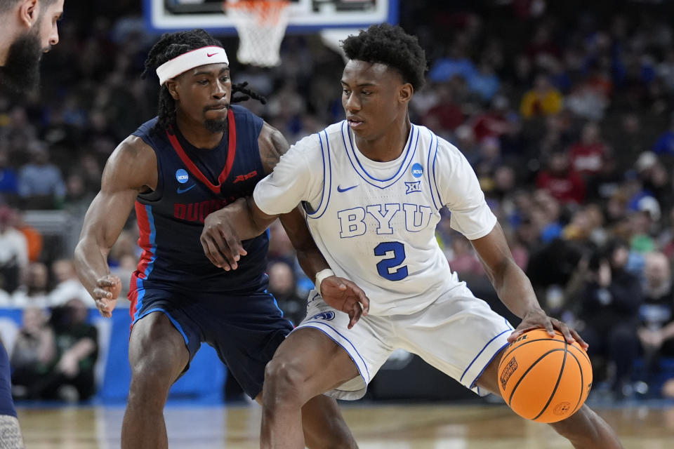 BYU guard Jaxson Robinson (2) drives on Duquesne guard Jimmy Clark III (1) in the first half of a first-round college basketball game in the NCAA Tournament, Thursday, March 21, 2024, in Omaha, Neb. (AP Photo/Charlie Neibergall)