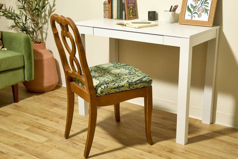 head on shot of the finished reupholstered chair in front of the desk.