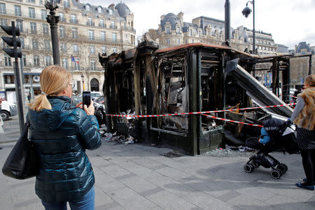 People take pictures of a newspaper kiosk burned during the last "yellow vests" protest on the Champs Elysees avenue in Paris, France, March 18, 2019. REUTERS/Philippe Wojazer