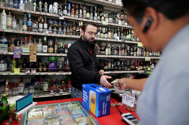 FILE PHOTO: Ibrahim Yacop, 36, owner of 7 Days Liquor, sells beer to a customer during the global outbreak of coronavirus disease (COVID-19) in Glendale