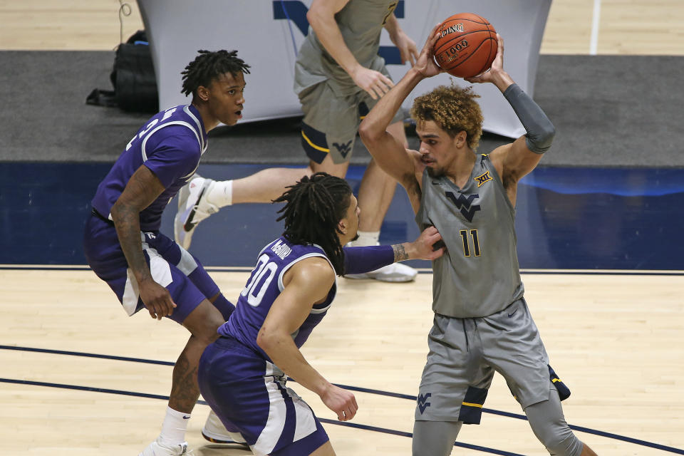 West Virginia forward Emmitt Matthews Jr. (11) is defended by Kansas State guards DaJuan Gordon (3) and Mike McGuirl (0)] during the first half of an NCAA college basketball game Saturday, Feb. 27, 2021, in Morgantown, W.Va. (AP Photo/Kathleen Batten)