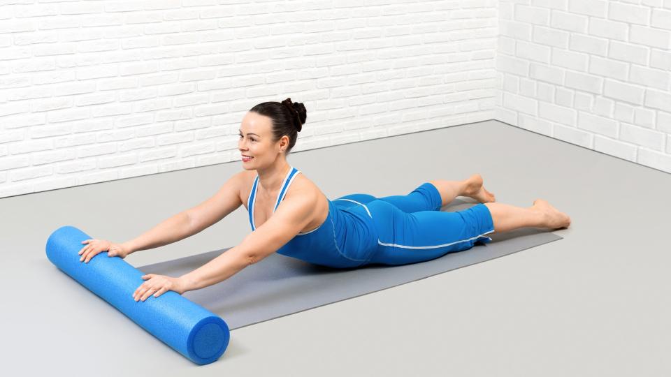 Woman performing a back extension stretch using a bolster