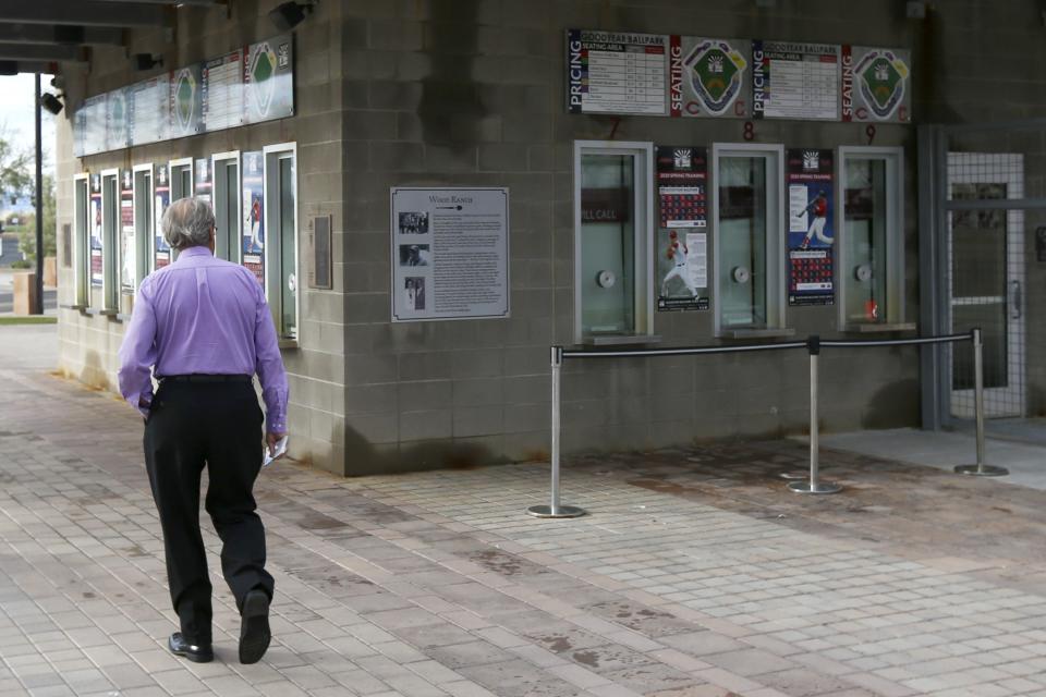 A ticket holder walks around the outside of Goodyear Ballpark, spring training home of the Cleveland Indians and Cincinnati Reds baseball teams, looking to get a refund on his canceled game tickets Thursday, March 12, 2020, in Goodyear, Ariz. Major League Baseball has suspended the rest of its spring training game schedule because if the coronavirus outbreak. MLB is also delaying the start of its regular season by at least two weeks. (AP Photo/Ross D. Franklin)