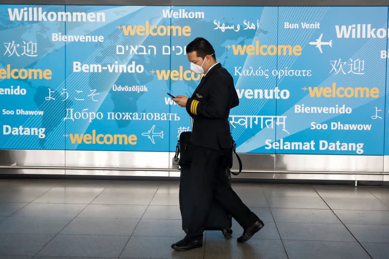 A member of a flight crew wears a face mask as he arrives at John F. Kennedy International Airport in New York