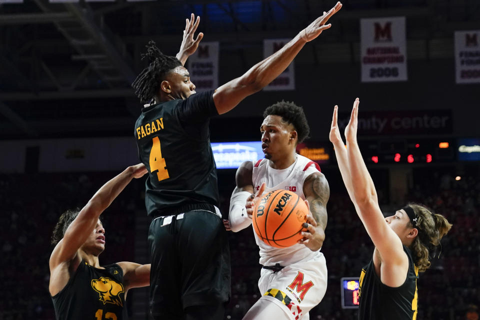 Maryland guard Jahmir Young passes the ball as UMBC guard Dion Brown, left, forward Tra'Von Fagan (4) and guard Jacob Boonyasith defend during the second half of an NCAA college basketball game Thursday, Dec. 29, 2022, in College Park, Md. (AP Photo/Jess Rapfogel)