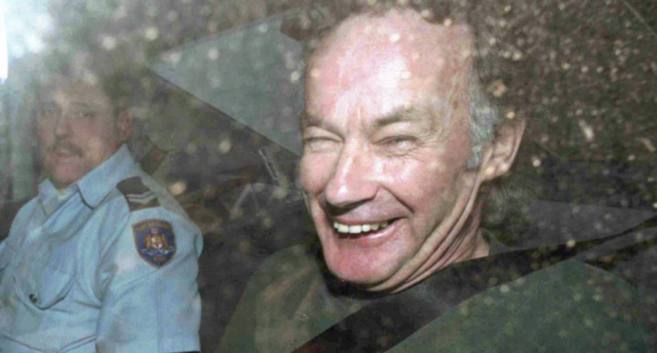 Ivan Milat (right with a police officer) smiles in a police car after attending a court in Sydney on November 4, 1997.