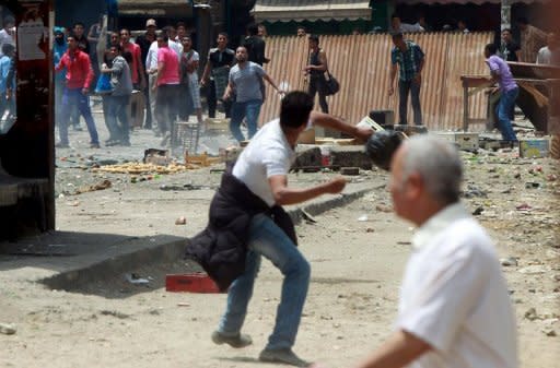 Unidentified Egyptians (top) throw stones at anti-military protesters during clashes in the Abbassiya district of Cairo. Thugs attacked an anti-military protest near the defence ministry in Cairo and 20 people were killed, officials said, in the politically tense run-up to the first post-uprising presidential election